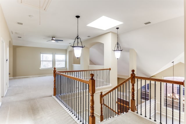 corridor with light carpet and vaulted ceiling with skylight