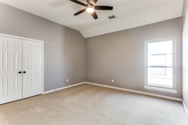 unfurnished bedroom with lofted ceiling, ceiling fan, light colored carpet, and a closet