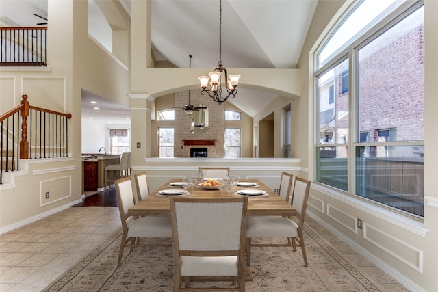 dining room with a healthy amount of sunlight, light tile patterned flooring, high vaulted ceiling, and a notable chandelier