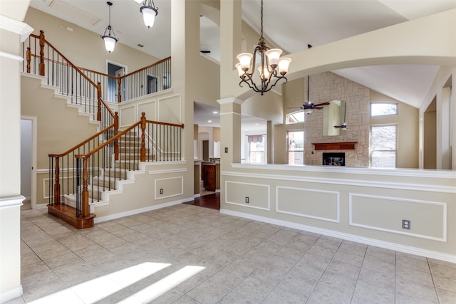 kitchen featuring light tile patterned flooring, a fireplace, ornate columns, and high vaulted ceiling