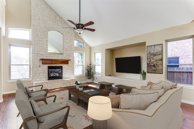 living room featuring ceiling fan, a stone fireplace, hardwood / wood-style floors, and high vaulted ceiling