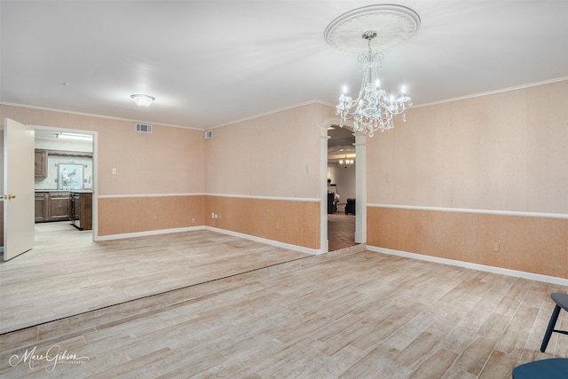 spare room featuring crown molding, light hardwood / wood-style flooring, and a chandelier