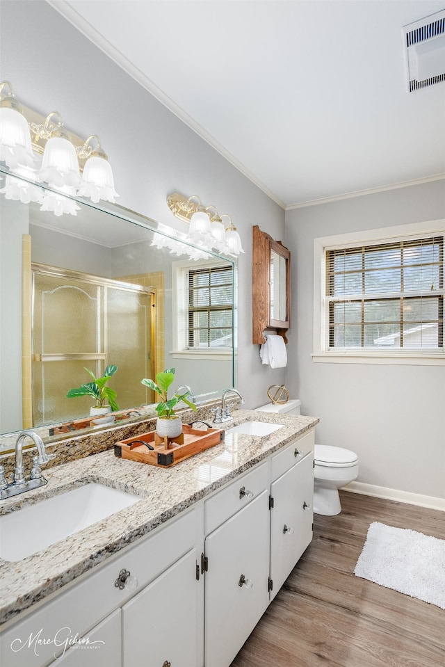 bathroom featuring toilet, wood-type flooring, ornamental molding, vanity, and walk in shower