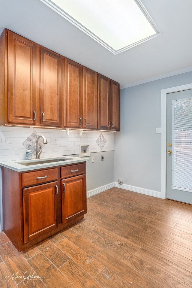 kitchen featuring ornamental molding, sink, wood-type flooring, and backsplash