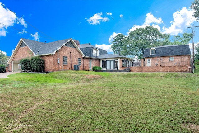 rear view of property featuring central AC, a yard, and a garage