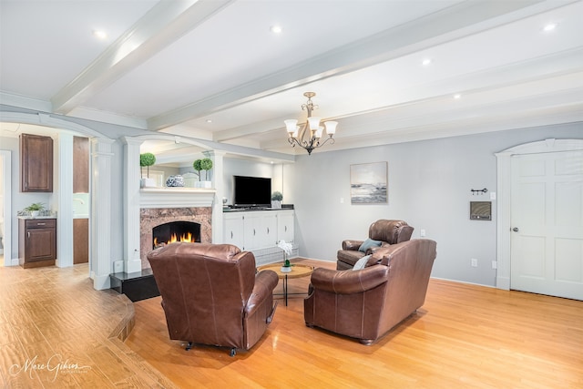 living room with beamed ceiling, light hardwood / wood-style flooring, an inviting chandelier, and a premium fireplace