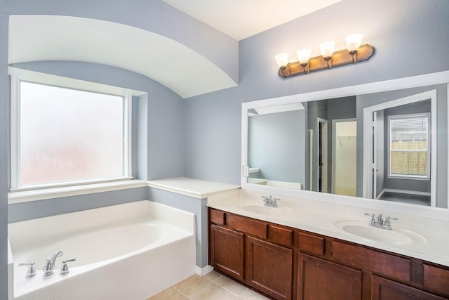 full bath featuring tile patterned flooring, a garden tub, a sink, and double vanity