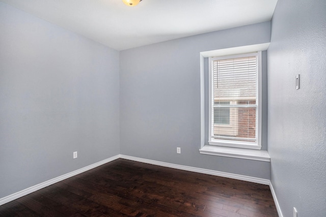 empty room featuring dark wood-style flooring and baseboards