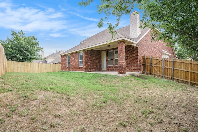 back of property with a patio area, brick siding, a yard, and a fenced backyard