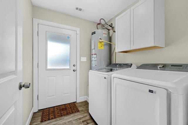 laundry area with light wood-type flooring, washer and clothes dryer, electric water heater, and cabinets