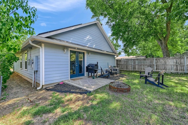 back of property featuring an outdoor fire pit, french doors, and a lawn