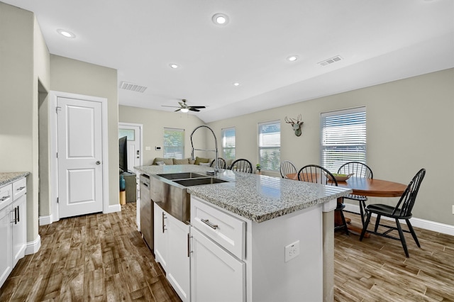 kitchen with ceiling fan, hardwood / wood-style flooring, and a kitchen island with sink