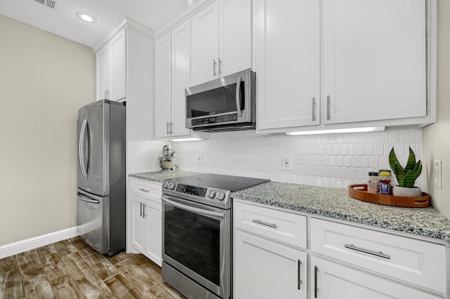 kitchen featuring stainless steel appliances, light hardwood / wood-style flooring, tasteful backsplash, and light stone counters