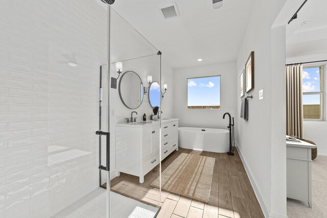 bathroom with vanity, independent shower and bath, and a wealth of natural light