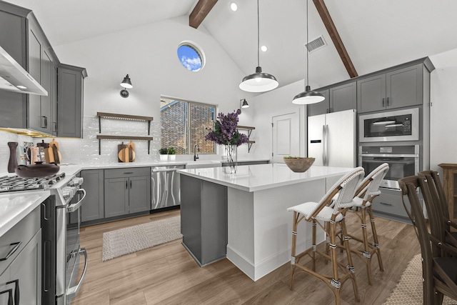 kitchen featuring stainless steel appliances, beamed ceiling, light hardwood / wood-style floors, decorative light fixtures, and decorative backsplash