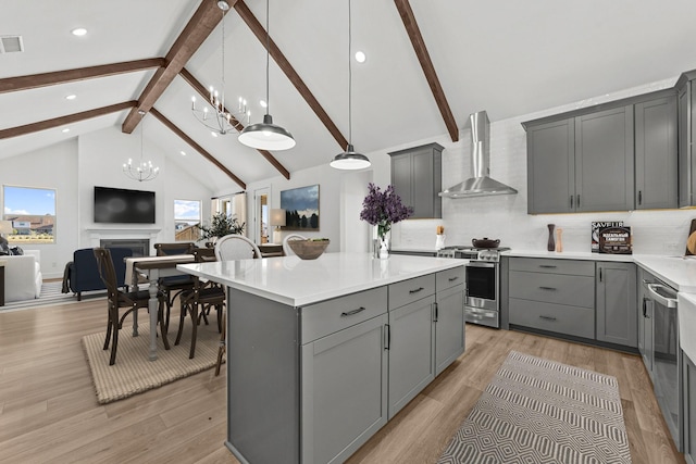 kitchen with wall chimney exhaust hood, gray cabinets, and appliances with stainless steel finishes