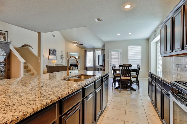 kitchen featuring light stone countertops, appliances with stainless steel finishes, a healthy amount of sunlight, sink, and light tile patterned flooring