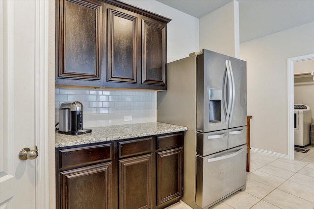 kitchen with light stone countertops, stainless steel fridge, backsplash, dark brown cabinets, and washer / clothes dryer