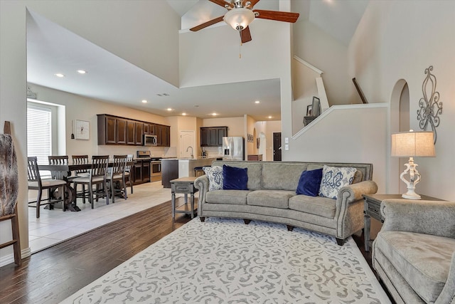 living room featuring light hardwood / wood-style floors, high vaulted ceiling, and ceiling fan