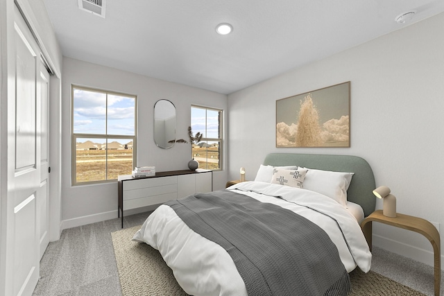 carpeted bedroom with a closet, visible vents, and baseboards