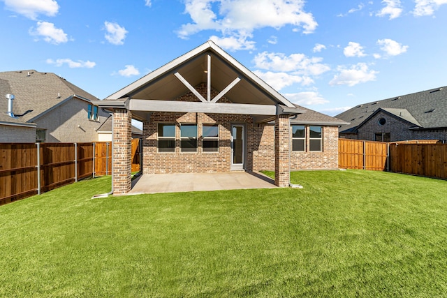 rear view of property with a patio area, brick siding, a lawn, and a fenced backyard