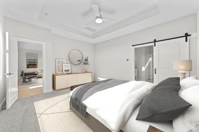 bedroom featuring a raised ceiling, visible vents, and a barn door