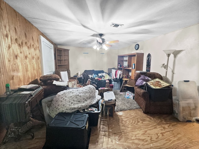 living room with ceiling fan and wooden walls