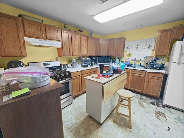 kitchen featuring a breakfast bar, gas stove, white refrigerator, and a kitchen island