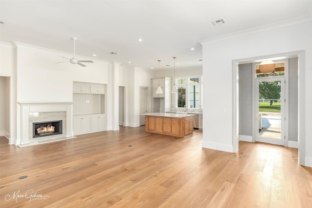 unfurnished living room featuring a healthy amount of sunlight, ceiling fan, light hardwood / wood-style flooring, and a premium fireplace