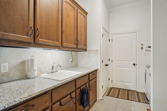 kitchen featuring light tile patterned flooring, backsplash, light stone counters, sink, and ornamental molding