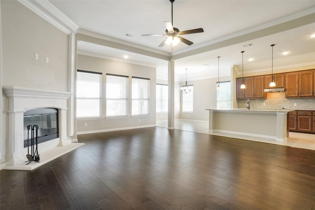 unfurnished living room with crown molding, a wealth of natural light, and dark wood-type flooring