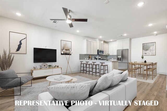 living room featuring ceiling fan and light hardwood / wood-style flooring