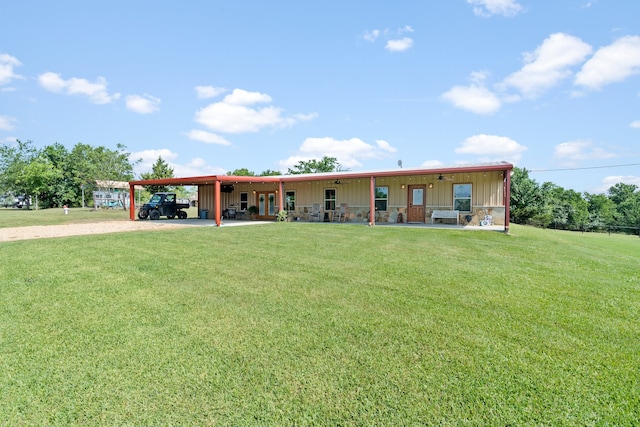 back of house with a carport, stone siding, a lawn, and driveway