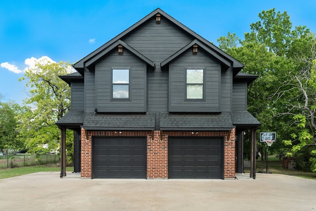 exterior space featuring an attached garage, concrete driveway, brick siding, and a shingled roof