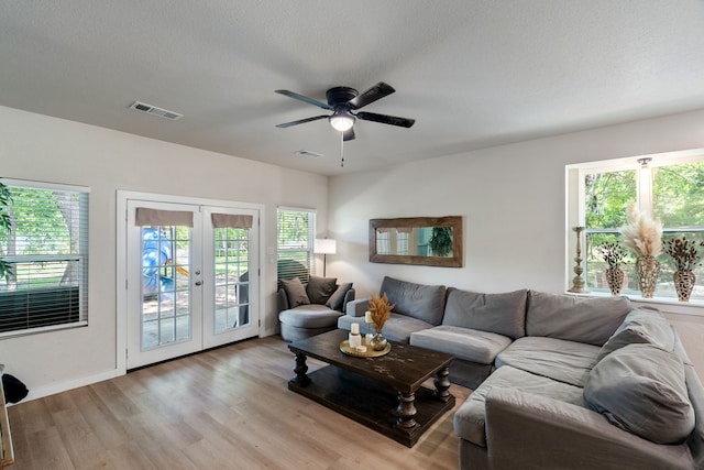 living area with light wood-style floors, french doors, visible vents, and a healthy amount of sunlight