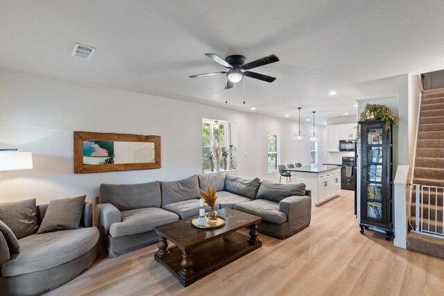 living room with light hardwood / wood-style floors and ceiling fan