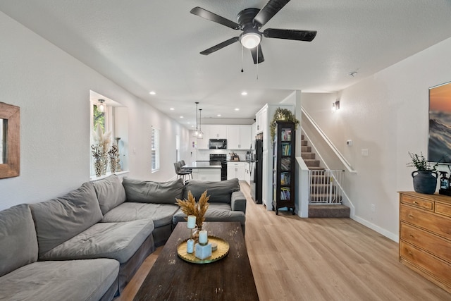 living room with light wood finished floors, baseboards, a ceiling fan, stairs, and recessed lighting