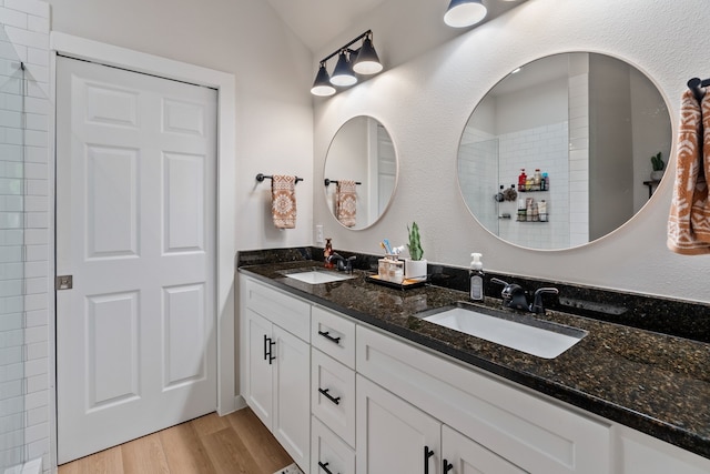 bathroom with lofted ceiling, double vanity, wood finished floors, and a sink