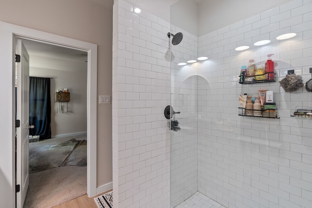 full bath featuring tiled shower, wood finished floors, and baseboards