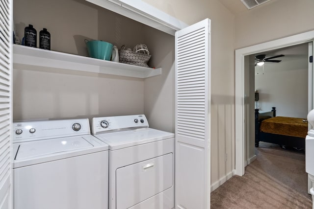 clothes washing area featuring a ceiling fan, laundry area, light colored carpet, and washer and clothes dryer