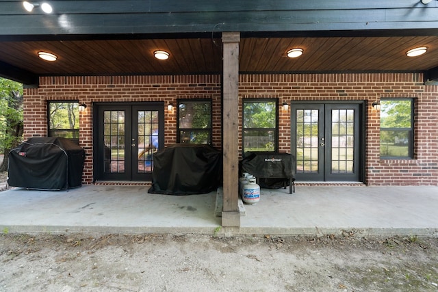 property entrance featuring a patio area, french doors, and brick siding