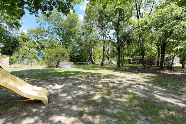 view of yard featuring a trampoline, fence, and a playground