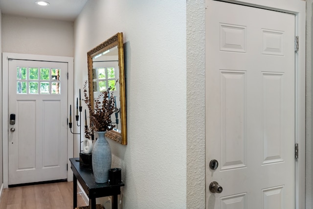 doorway featuring light wood-type flooring, a textured wall, and recessed lighting