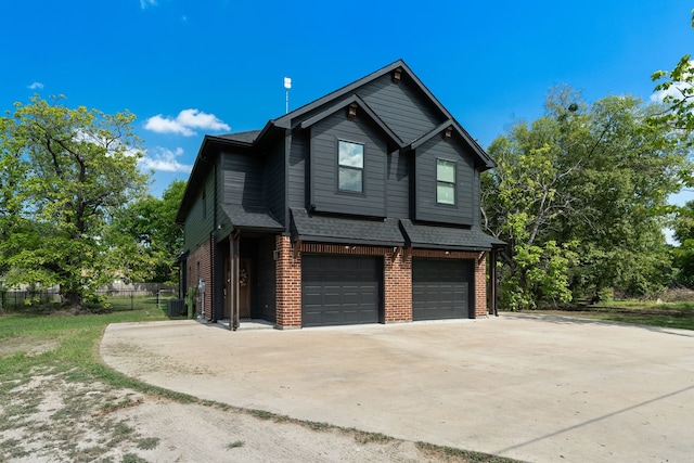 view of side of home with a garage, driveway, roof with shingles, fence, and brick siding