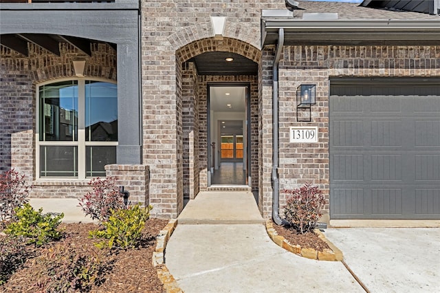 property entrance featuring a garage, brick siding, driveway, and a shingled roof