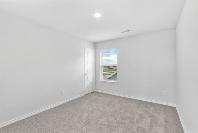 empty room featuring carpet floors, visible vents, and baseboards