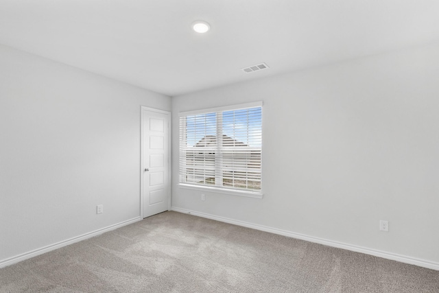 spare room featuring carpet, visible vents, and baseboards