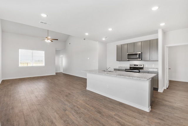 kitchen with appliances with stainless steel finishes, ceiling fan, a center island with sink, and dark hardwood / wood-style floors