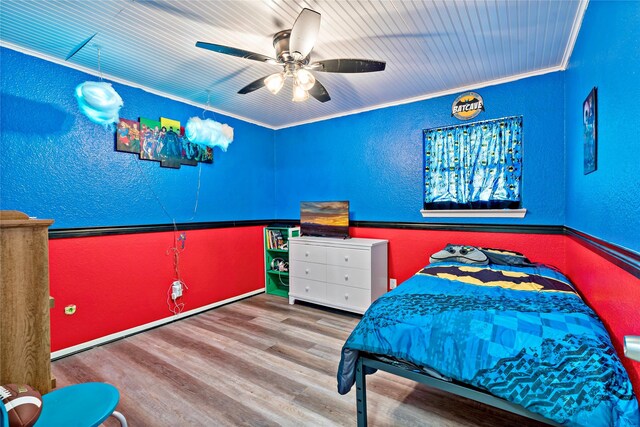 bedroom with ceiling fan, ornamental molding, and wood-type flooring