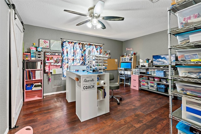 office with a barn door, a textured ceiling, a ceiling fan, and wood finished floors